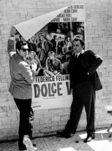 Federico Fellini davanti al manifesto del film Dolce Vita